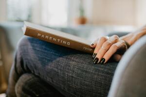 Woman's hand holding book titled, "Parenting"